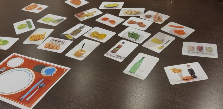 Cartes représentant différents aliments disposées sur une table pour un exercice de composition de repas